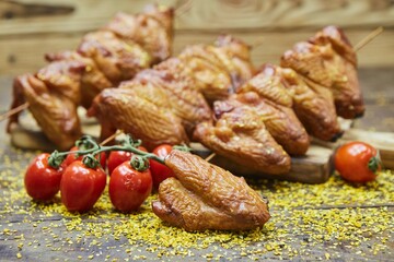 Smoked chicken wings surrounded by vegetables. Breakfast products. Meat production
