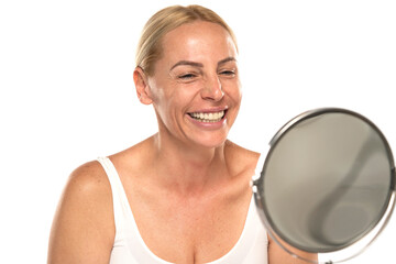 Happy senior woman without make up Close up face of a mature blonde woman smiling in the mirror on...