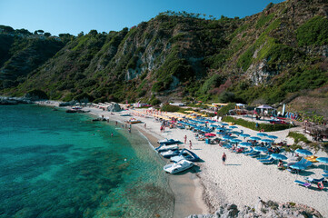Fototapeta na wymiar Italy, July 2023: view of the spectacular and relaxing Grotticelle beach near Capo Vaticano in Calabria. You notice the rocks and the bathers having fun during their vacation