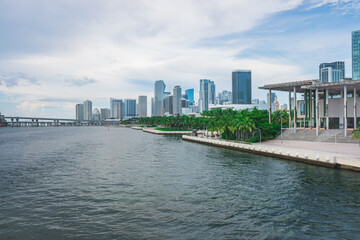 Miami skyline is stunning with towering buildings beside Biscayne Bay. Lush green trees in Maurice...
