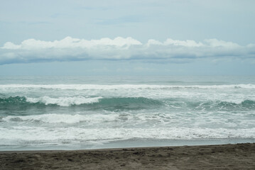 Fototapeta na wymiar Landscape of a beach on the Mexican Pacific coast. Sea with many waves and cloudy sky.