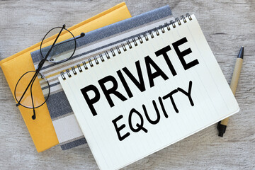 wooden table.yellow notepad and open notebook with text Private equity