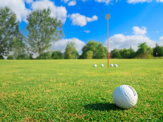 Close-up golf ball on tee with blur green bokeh background.