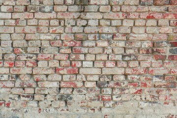 Zdjęcie przedstawiające teksturę utworzoną przez cegły ułożone w równych rzędach w murze. Cegły częściowo pokryte są zaprawą murarską. Stanowią one element starej budowli. - 629309850