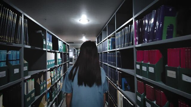slow motion Rear view of female employee searching for documents in the warehouse where important documents and confidential information are kept at the office
