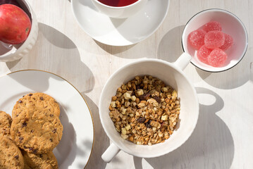 Healthy breakfast. Muesli, cup of tea, cookies, marmalade, apple and nectarine on white wooden...