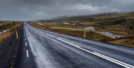 Highway road and mountain view during auto trip in Iceland. Spectacular Icelandic landscape with  scenic nature: highland mountains, fields, clouds, glaciers, waterfalls.