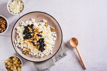 Soft cottage cheese with blackcurrant and walnuts on a breakfast plate top view