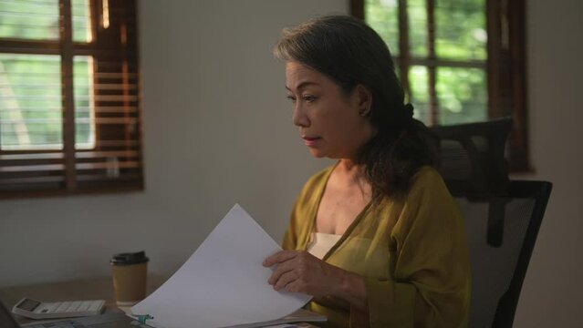 Asian female senior entrepreneur using her laptop at home.