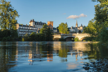 Fototapeta na wymiar View of the Castle of Pau, the XIV juillet bridge and the gave de Pau at sunset, with reflection on the water