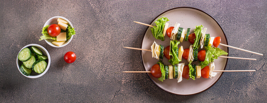 Fresh tomato, cucumber, cheese, tortilla and lettuce canape on a plate top view web banner