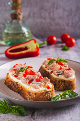 Open sandwiches with canned tuna, pepper and basil on cream cheese on a plate vertical view