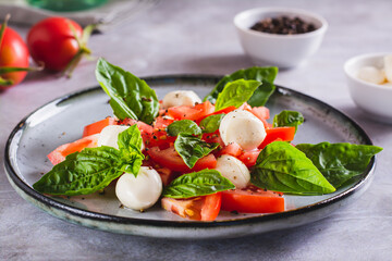 Caprese salad with tomatoes, mozzarella, basil and olive oil on a plate