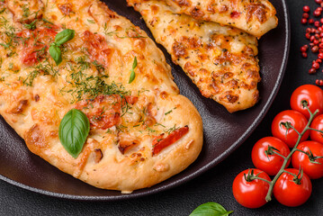 Delicious oven fresh flatbread pizza with cheese, tomatoes, sausage, salt and spices