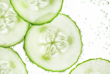 background of sliced cucumber slices with air bubbles on the water surface, top view