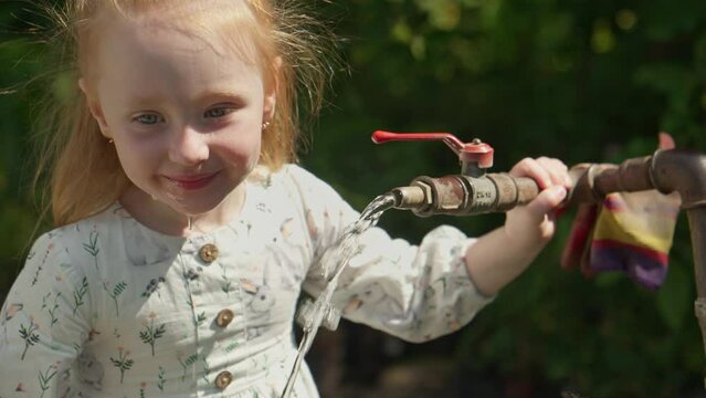 Little child girl funny catch water. Kid trying to lick water like dog. Girl drinking fresh water. Funny child. 4K, UHD