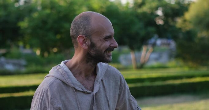 A man gazes at the camera, initially startled by something, but soon bursts into laughter, finding humor in his own momentary fear