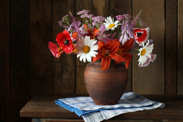 poppies, lilies, daisies and yarrow. Garden flowers in a clay jug.