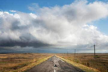 View of an old abandoned road in the steppe beautiful landscape with clouds. Freedom and travel. © Anna