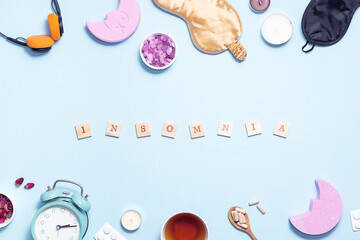 Insomnia concept. Alarm clock, sleeping mask, herbal tea, aromatic salt and natural pills on light blue background top view.