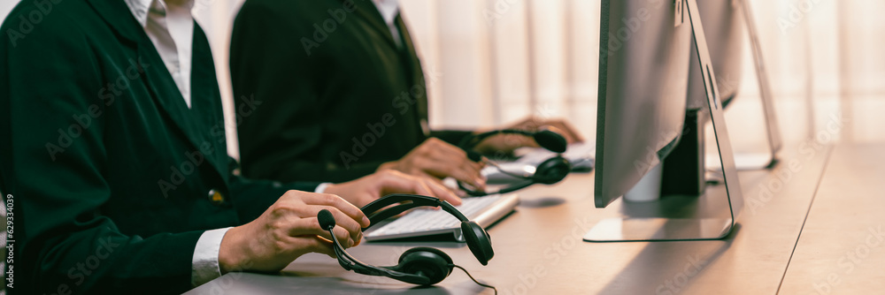 Aufkleber panorama focus hand holding headset on call center workspace desk with blur background of operator t