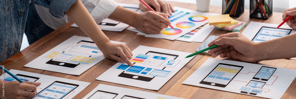 Poster Panorama shot of front-end developer team brainstorming UI and UX designs for mobile app on paper wireframe interface. User interface development team planning for user-friendly UI design. Scrutinize