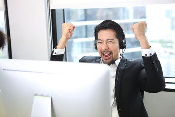  Successful business professionals. Happy attractive businessman , Call center worker accompanied by her team. Smiling customer support operator at work. Young employee working with a headset.