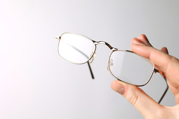 glasses for vision correction in the hand on a colored background with space for text