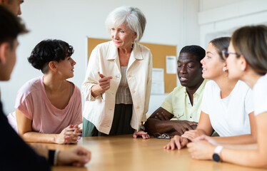 Elderly teacher, together with students of different ages, conducts round-table classes in the...