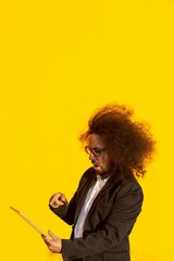 Businessman with long hair and glasses holding a tablet over yellow background
