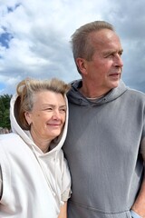 Portrait of happy elderly senior couple in love walking on a beach at summer, smile, laugh, have fun 