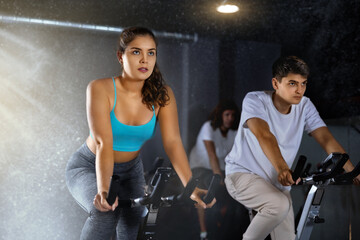 Woman and man doing cardio workout out, training on exercise bike