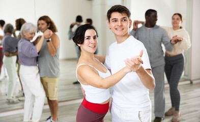 Fototapeta na wymiar Dancing positive couple learns a slow foxtrot in a lesson in a dance studio