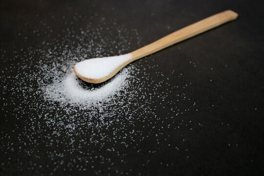 Natural sweetener on a wooden spoon, dark grey marble table