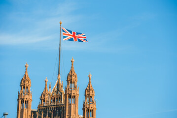 Single Union Jack flag waving in front of Big Ben at the Houses of Parliament in London, UK on a clear sunny day