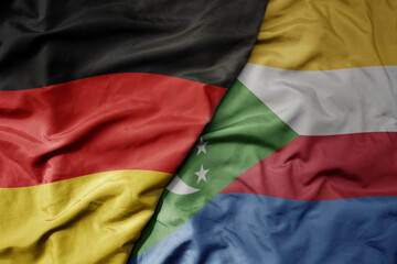 big waving realistic national colorful flag of germany and national flag of comoros .