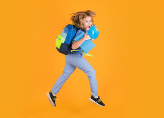 Fototapeta na wymiar Full length of excited kid jumping. Funny excited school concept. Little student boy with backpack go to study, jumping. Schoolchild, pupil jump on yellow isolated background.
