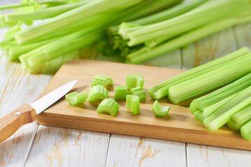 Cut fresh green celery in a white wooden table, selective focus.