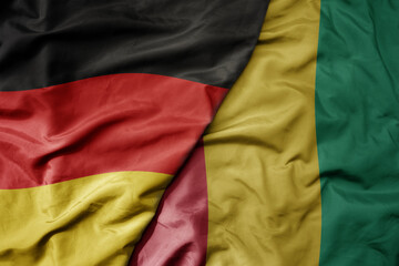 big waving realistic national colorful flag of germany and national flag of guinea .
