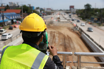 Civil or survey technician working at a new road construction site with a walkie-talkie and survey...