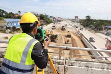 Civil or survey technician working at a new road construction site with a walkie-talkie and survey...