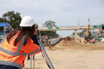 Site female  engineer operating her instrument during roadworks. Builder using total positioning...