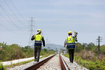 two surveyors hold the tripod of a geography camera on the railway