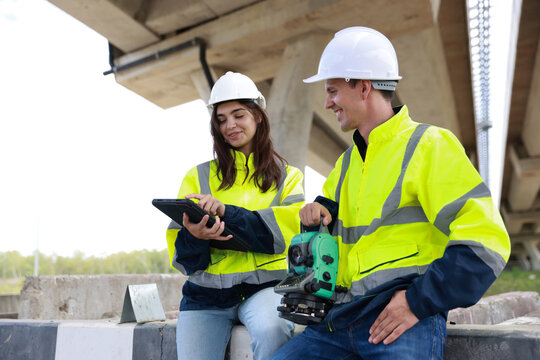 a couple of civil engineer work at the construction site to progress the building project - Powered by Adobe