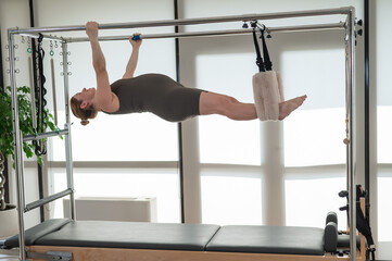 Pregnant woman doing pilates on a reformer. 