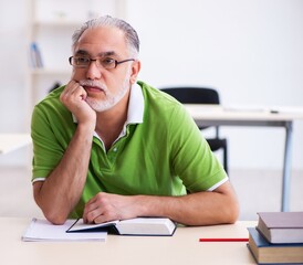 Old male student preparing for exams in the classroom