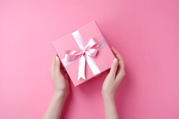 Female hands holding pink giftbox on the pink background, top view. Generative AI