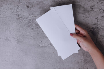 Hand holding white blank flyer over gray background to replace your design