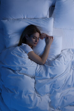 Woman sleeping in bed at night, above view