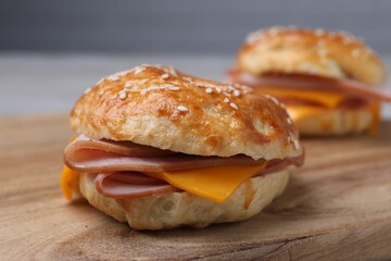 Delicious bagels with ham and cheese on wooden table, closeup